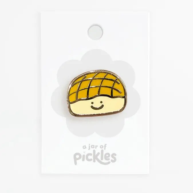 A cute enamel pin shaped like a smiling pineapple bun