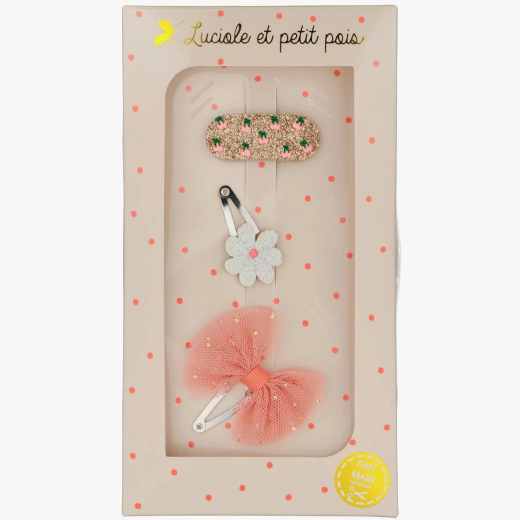 A set of three hair clips in a packaging, featuring a daisy-shaped clip, a tutu bow clip, and a clip with cherries and pearls design, all with a beige background and polka dots.