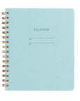 A planner with a light blue cover and brass wire-o binding.