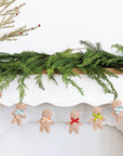Decorative Christmas mantel with greenery, gingerbread men garland, and a small tree.