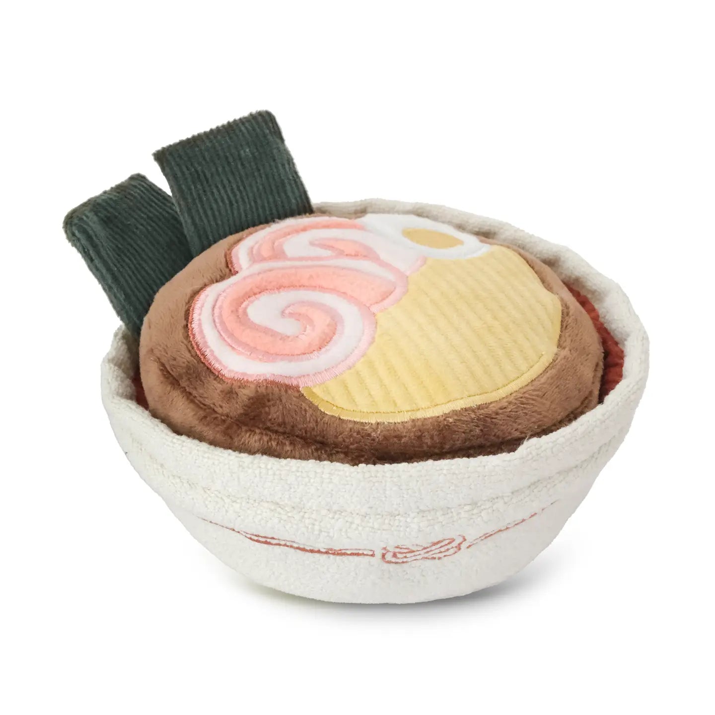 Plush dog toy resembling a bowl of ramen with a green seaweed on a white background