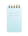 A blue notebook with a navy cover and gold wire-o binding, labeled with a title and date on the cover.