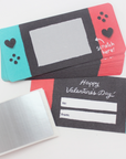 A collection of scratch-off Valentine's Day cards with game-themed designs, including images resembling a game controller and hearts, in red, gray, and turquoise colors.