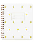 A white notebook with a letterpressed smiley face pattern and gold foil details on the cover, featuring a brass wire-o binding.