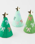 Three crepe paper Christmas trees in green, blue, and pink with star and bow decorations, wrapped in white tissue paper with a red round cord loop.