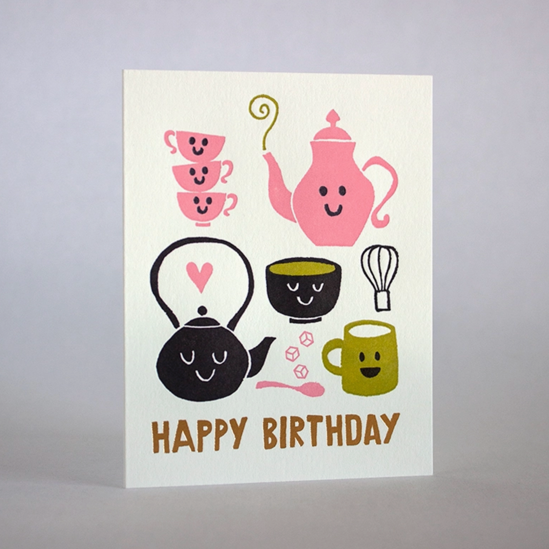 A tea party-themed birthday card with illustrations of a teapot, cups, and utensils, with gold foil details and the text 'Happy Birthday' on the front.