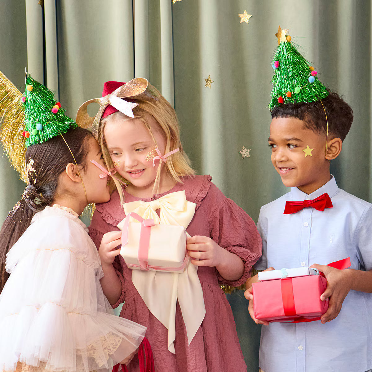 Children at a holiday party wearing tinsel christmas tree hats, holding gifts