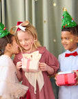 Children at a holiday party wearing tinsel christmas tree hats, holding gifts