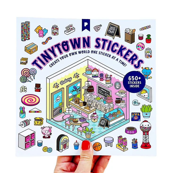 A hand with red nail polish holds a square sticker sheet featuring the 'Tinytown Stickers' design. The sticker sheet displays a colorful, illustrated bakery storefront with various themed stickers around it, including cupcakes, donuts, lollipops, and small characters.
