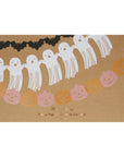 Halloween-themed tissue paper garlands with ghosts and pumpkins on a brown background.