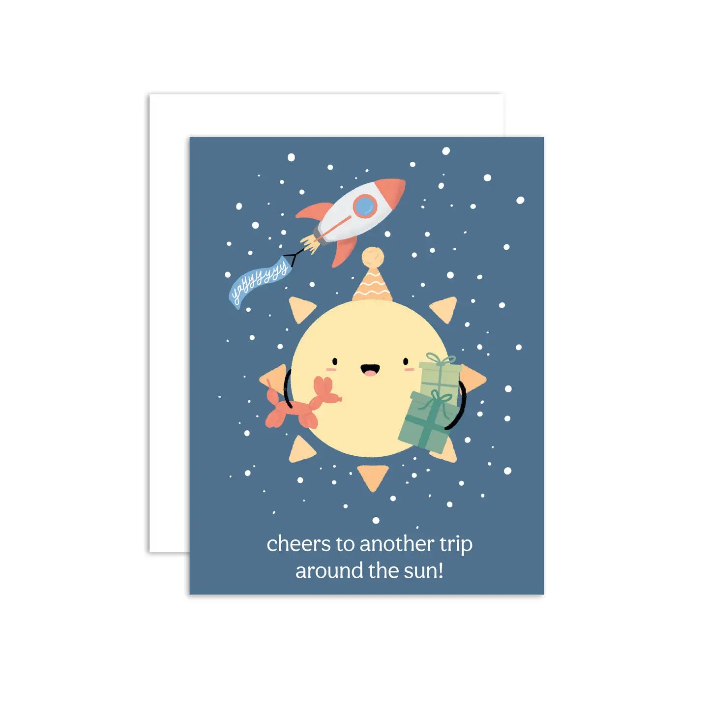 A greeting card with an illustration of a sun character with a party hat and a rocket in the background. The text on the card reads 'cheers to another trip around the sun!'.