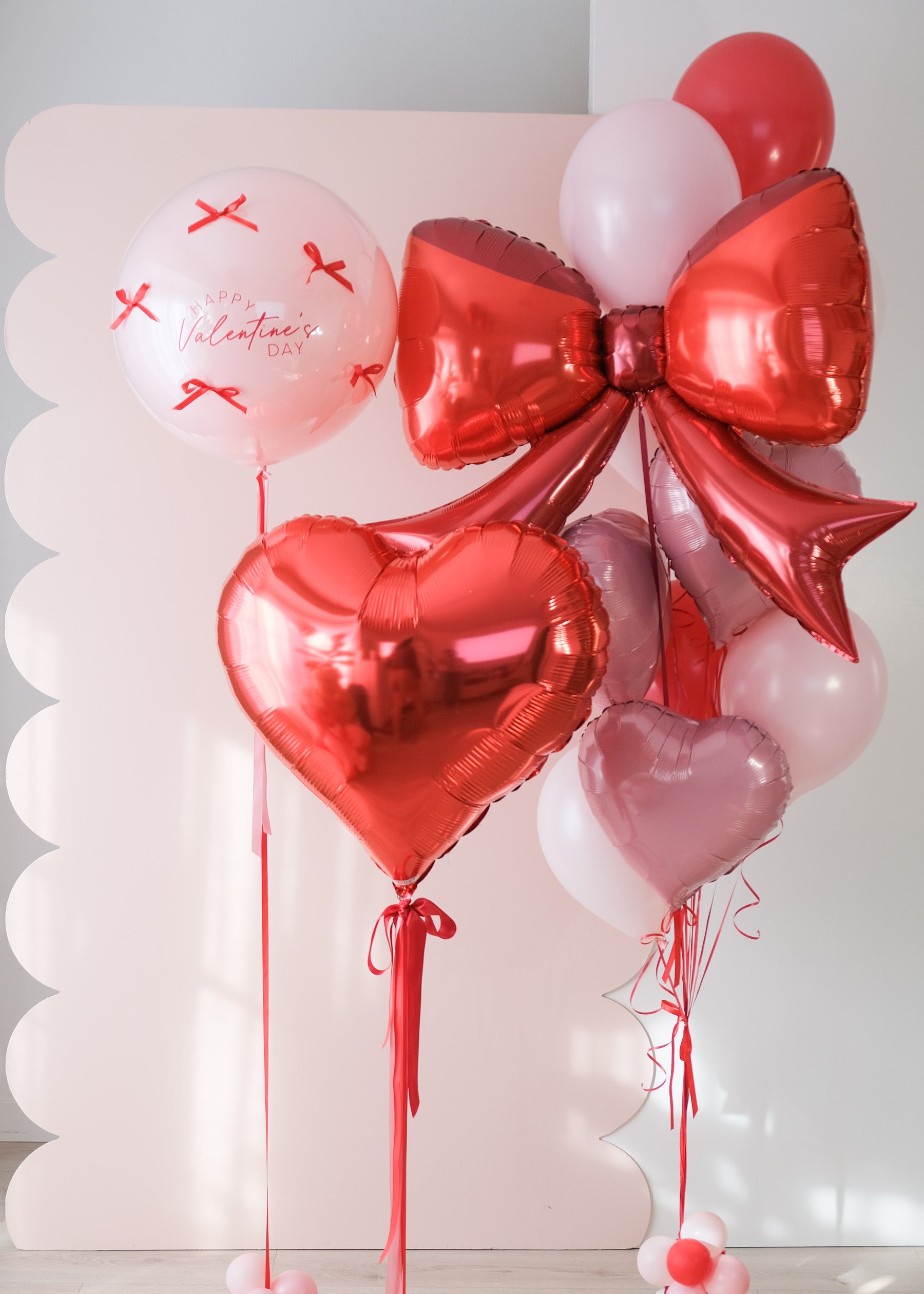 Valentine's Day-themed balloon bouquet with red and pink balloons on a light background