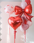 Valentine's Day-themed balloon bouquet with red and pink balloons on a light background