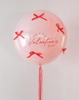 Pink balloon with 'Happy Valentine's Day' text and red bow ribbons