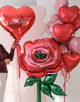 Valentine's Day-themed balloons including a heart-shaped balloon and a rose-shaped balloon with a person holding them.