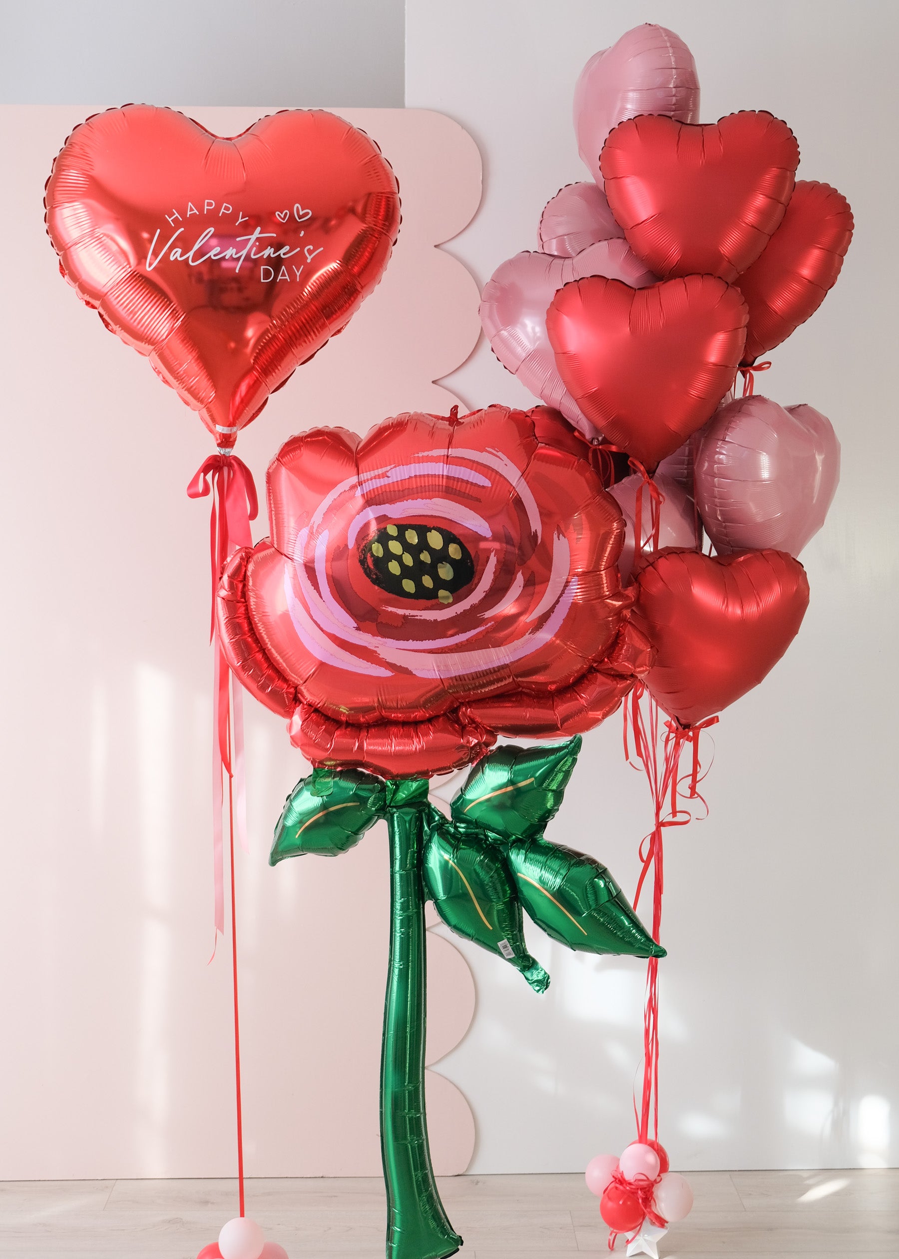 Valentine's Day-themed balloon bouquet trio with heart-shaped balloons, a large heart balloon, and a large flower balloon.