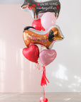Balloon bouquet with two dog-shaped balloons and heart balloons on a light background