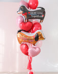 Large balloon bouquet with two dog-shaped balloons that say "We Be-Long Together" and "I Love You" with heart balloons