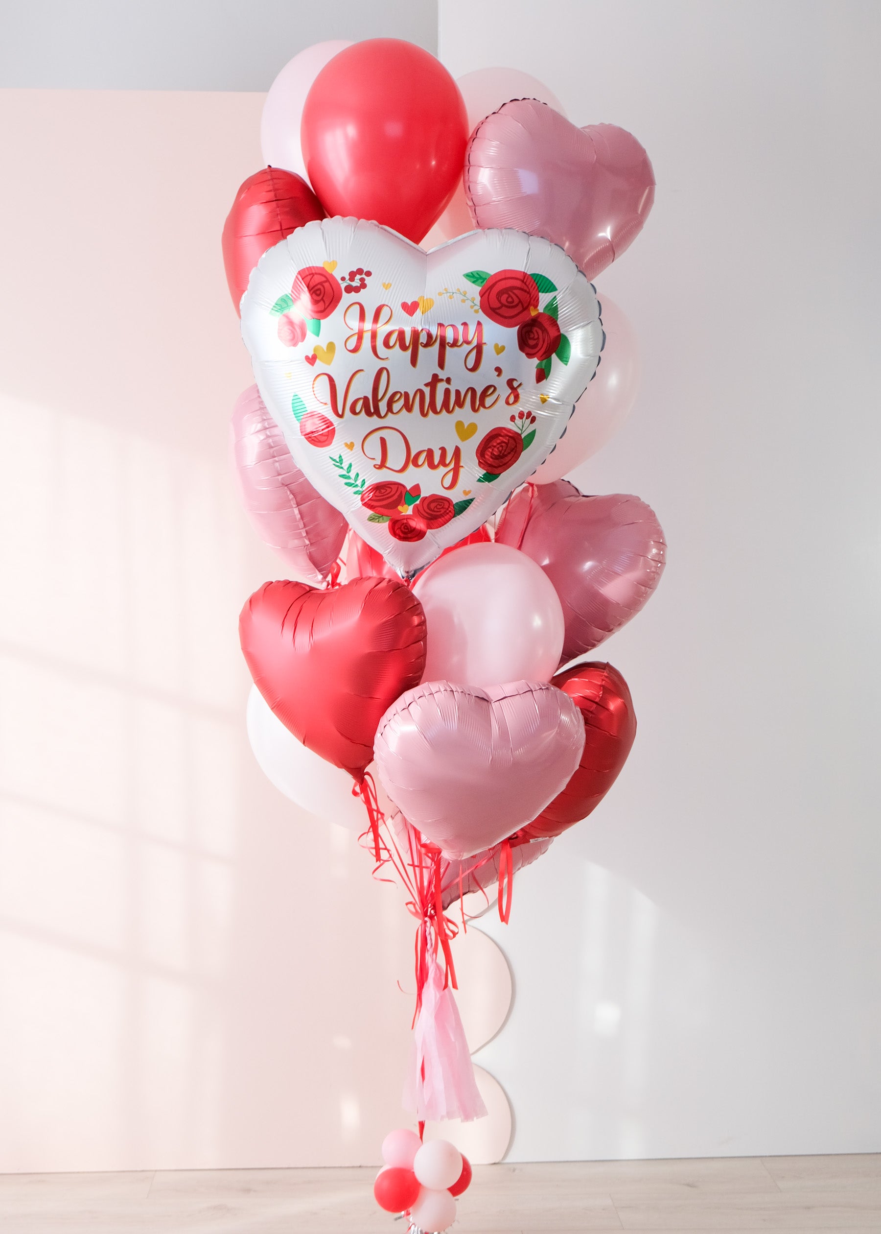 A large valentine's day balloon bouquet featuring a classic heart design with red rose print