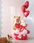 Corgi laying down next to a balloon cloud on the floor with capybara valentine's day balloon and daisy balloons
