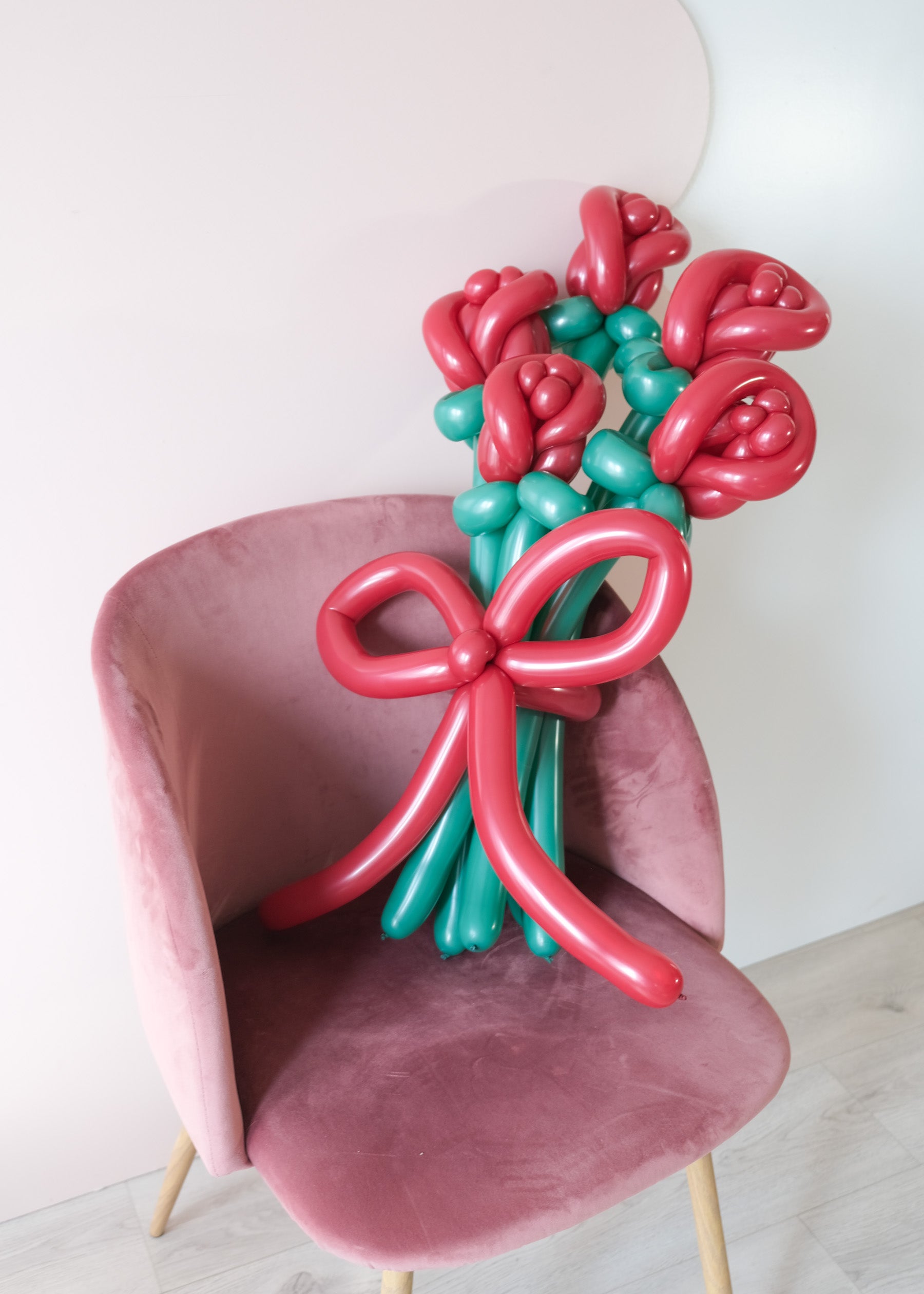 5 twisted balloon roses on a pink chair