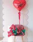 8-stem twisted rose balloon bouquet on a chair with red heart balloon 