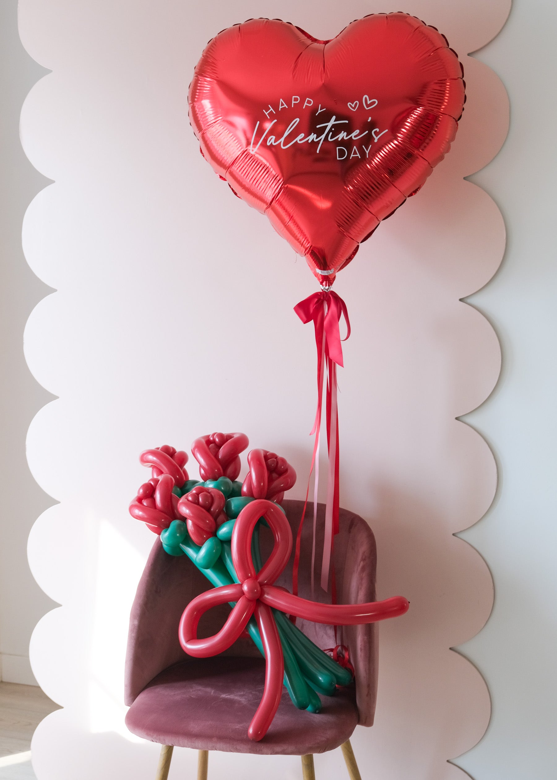 5 twisted balloon roses on a pink chair with a red happy valentine's day balloon heart
