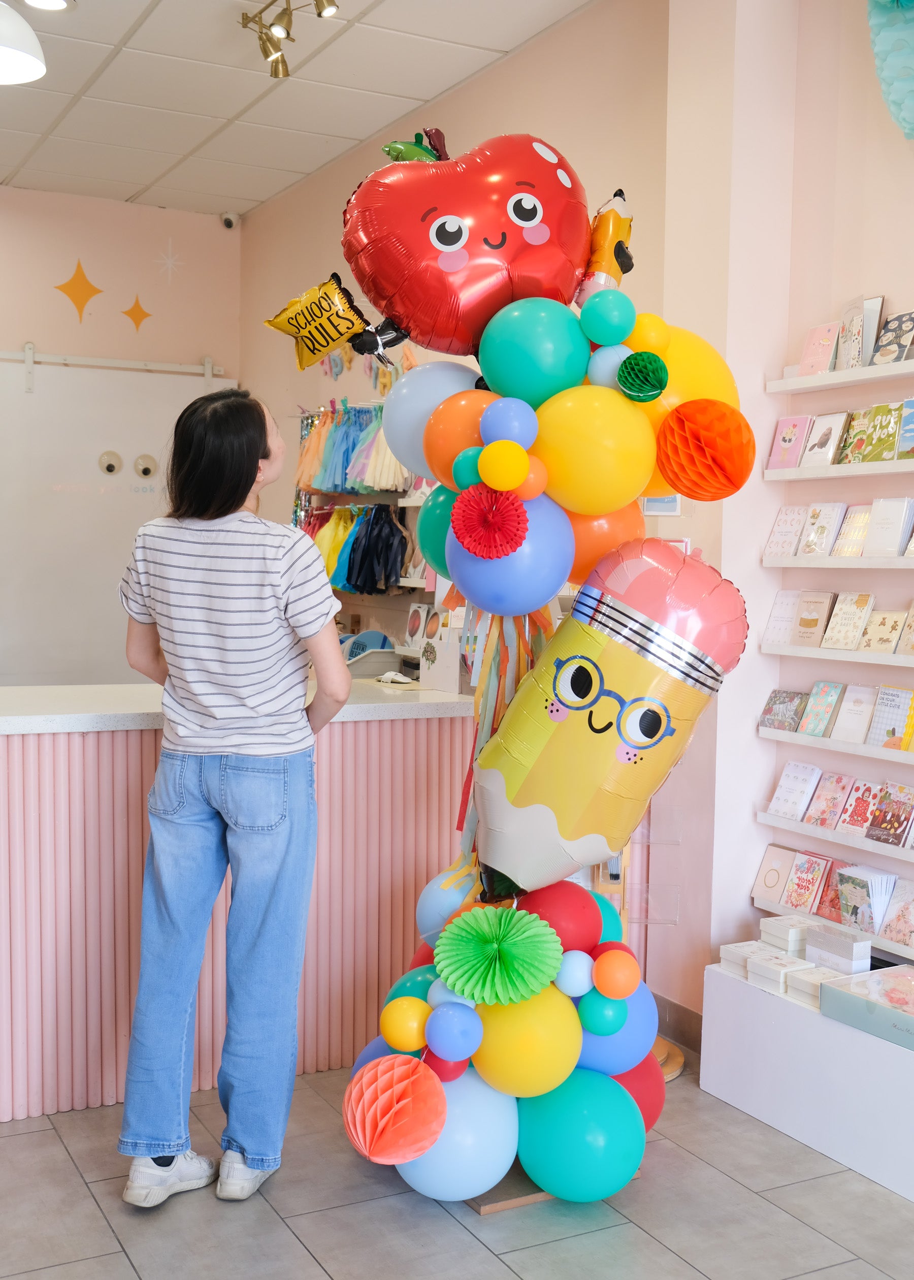 person standing next to deluxe balloon tower with back to school shapes