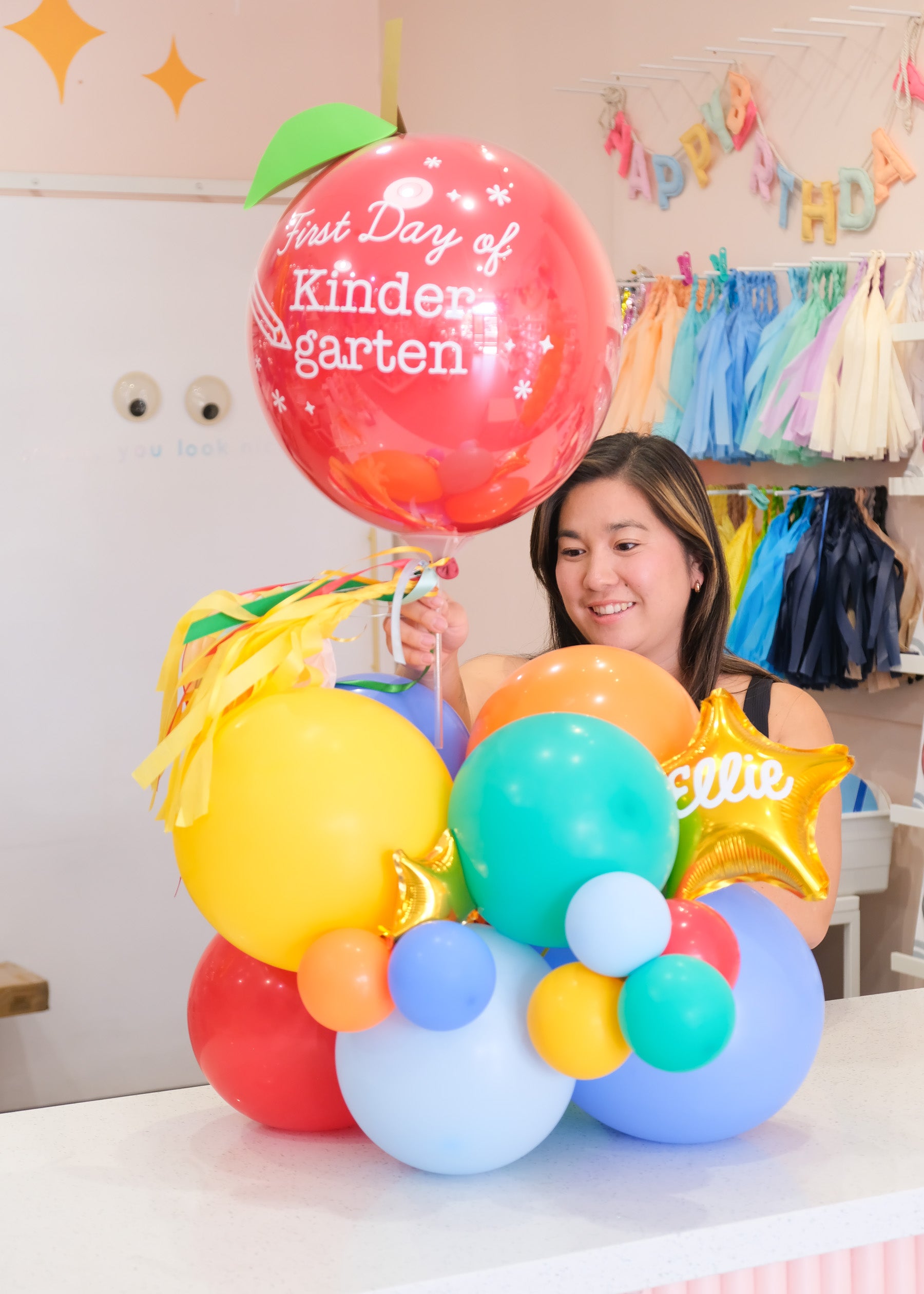 a woman holding an apple balloon with a tabletop balloon gift 