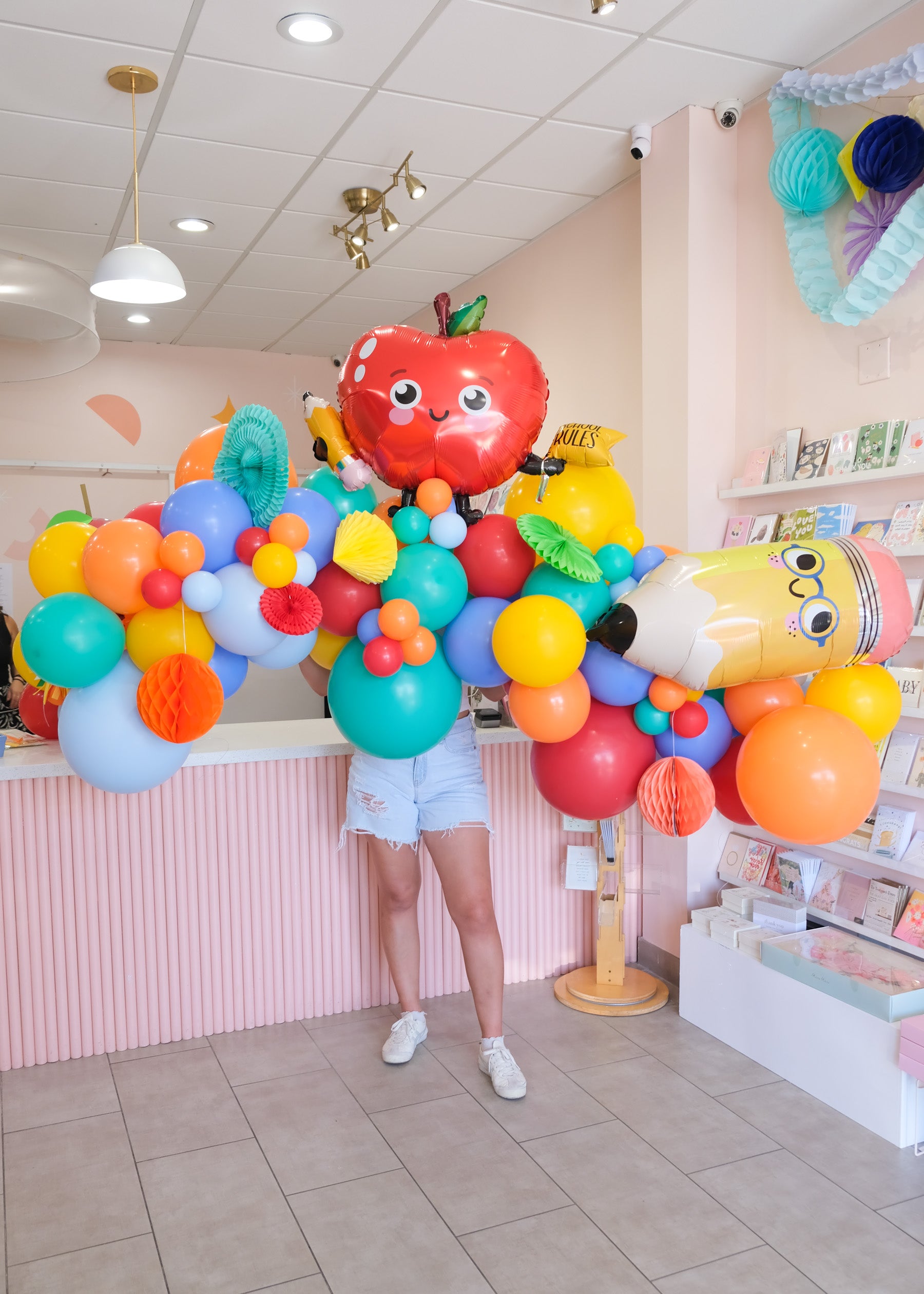 person holding a 7ft wide balloon garland with back to school themed shapes