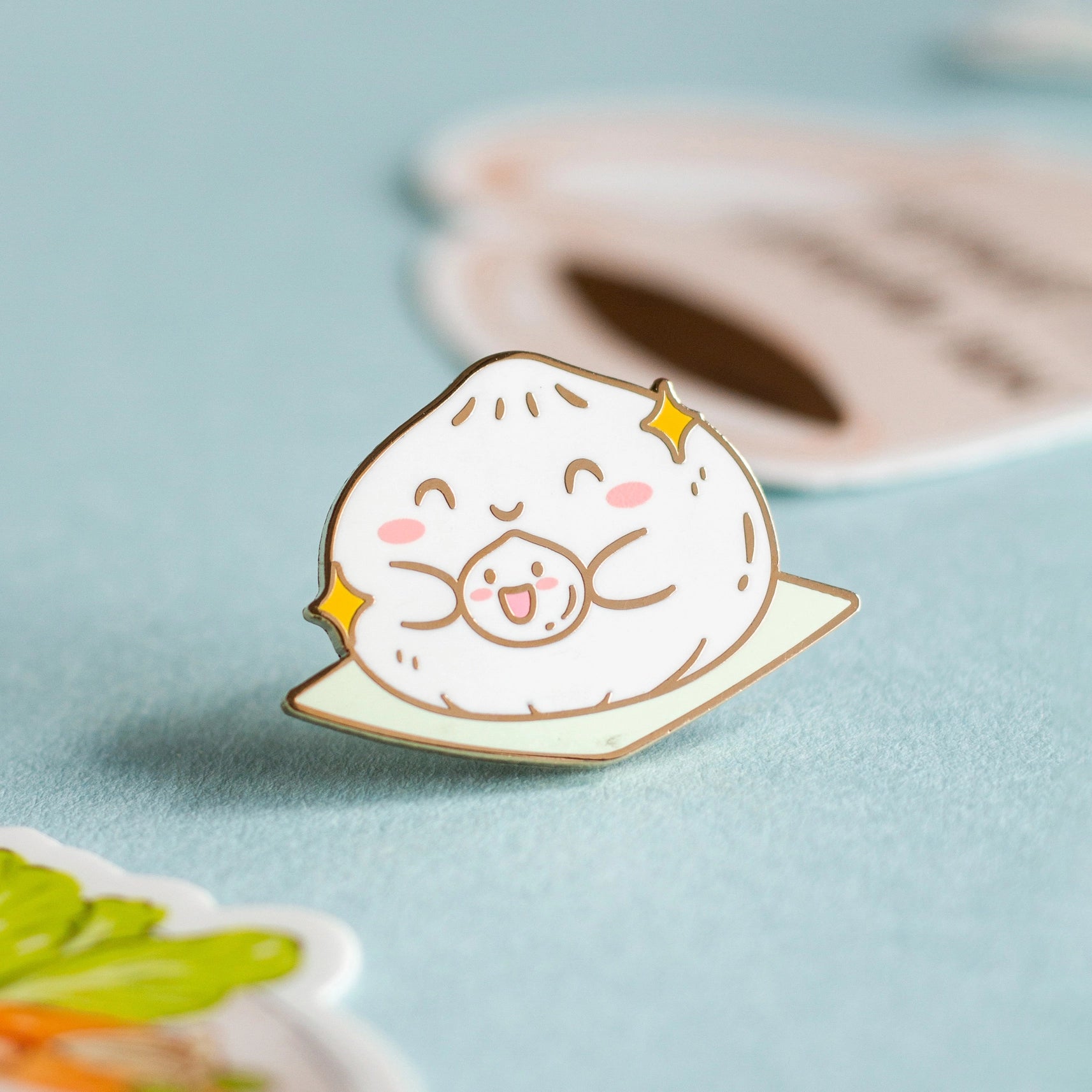 A enamel pin in the shape of a dumpling holding a smaller baby dumpling