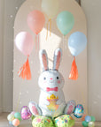 Sitting easter bunny balloon with an arch of floating pastel balloons