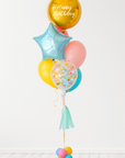 A balloon bouquet featuring a round gold orb balloon, with smaller multicolored balloons including pink, blue, and yellow, all adorned with confetti clear balloons and stars. The balloons are attached to a ribbon bow and tassel.