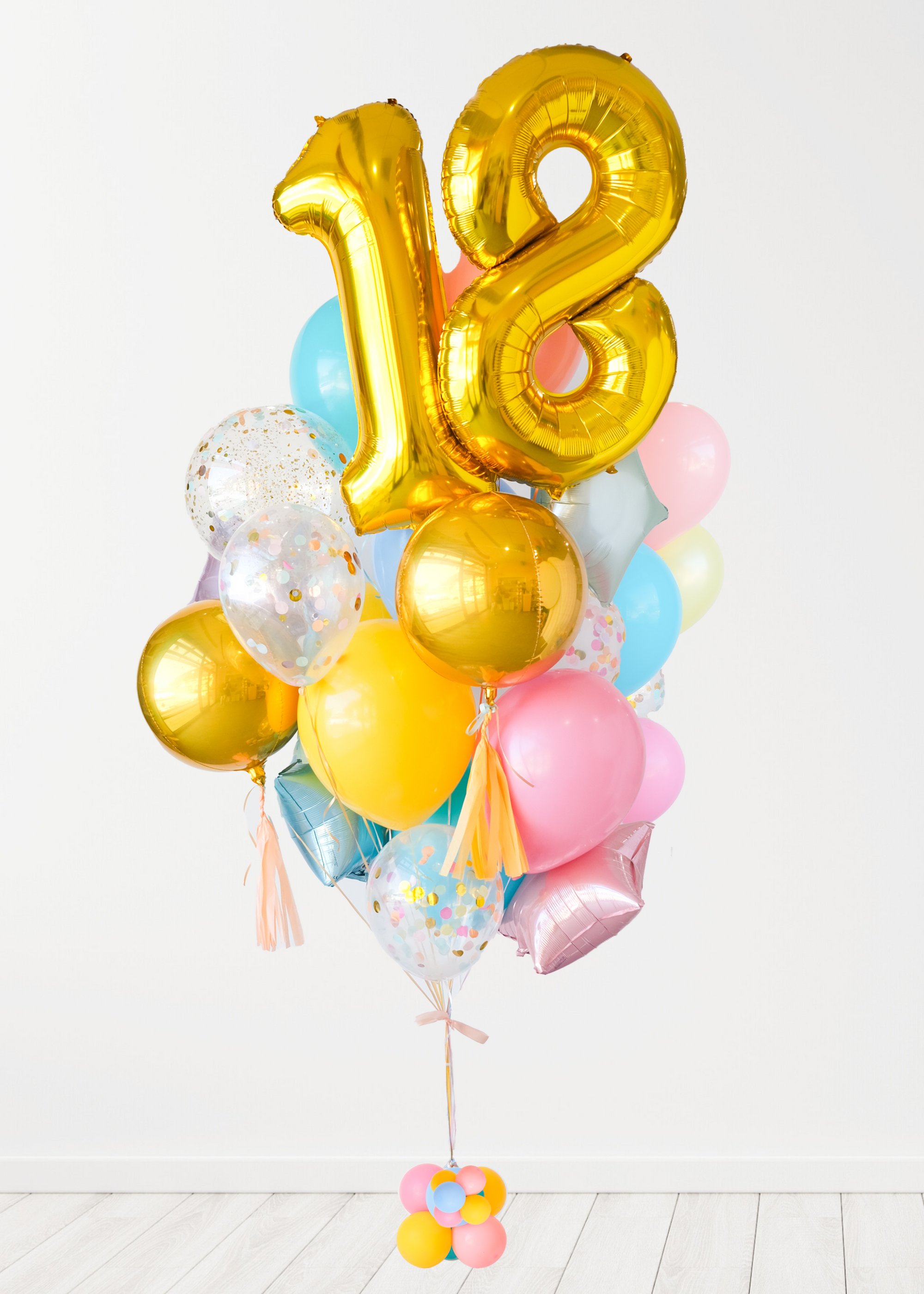 A balloon arrangement featuring a golden number '18' balloon with multicolored balloons tied to it, with the word 'Happy Birthday' printed on a gold balloon.