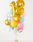 A balloon arrangement featuring a golden number '18' balloon with multicolored balloons tied to it, with the word 'Happy Birthday' printed on a gold balloon.