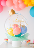 white box with clear balloon filled with mini balloons, with a "happy birthday" greeting and gold paper crown