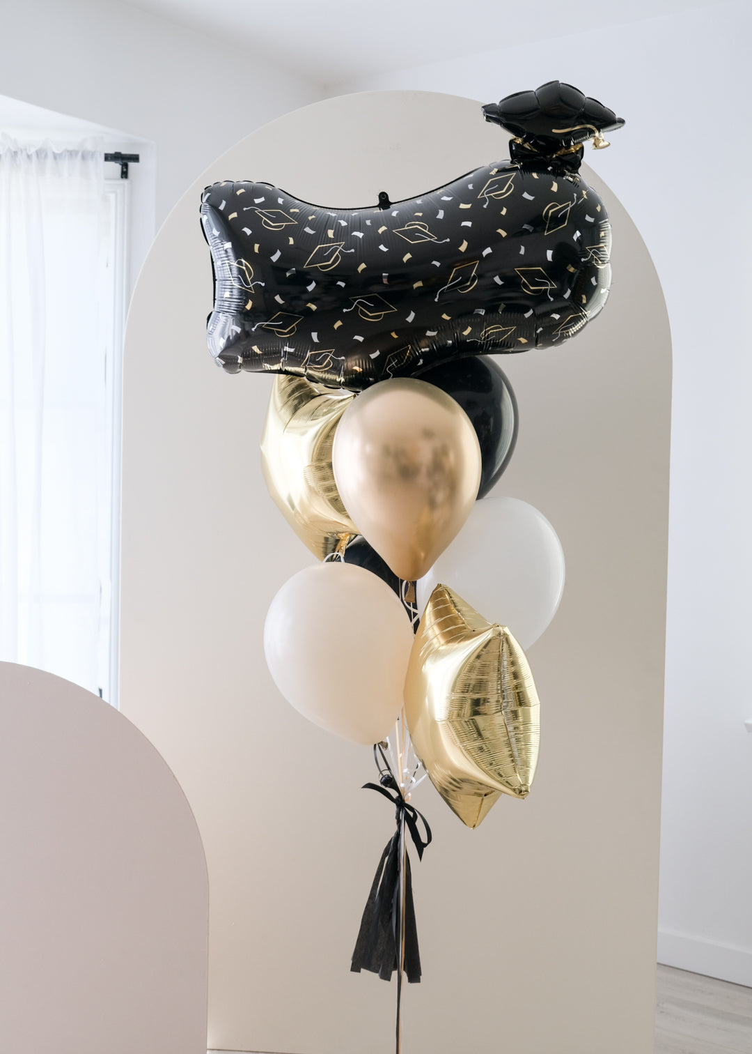 A balloon bouquet with black, gold, and silver balloons.