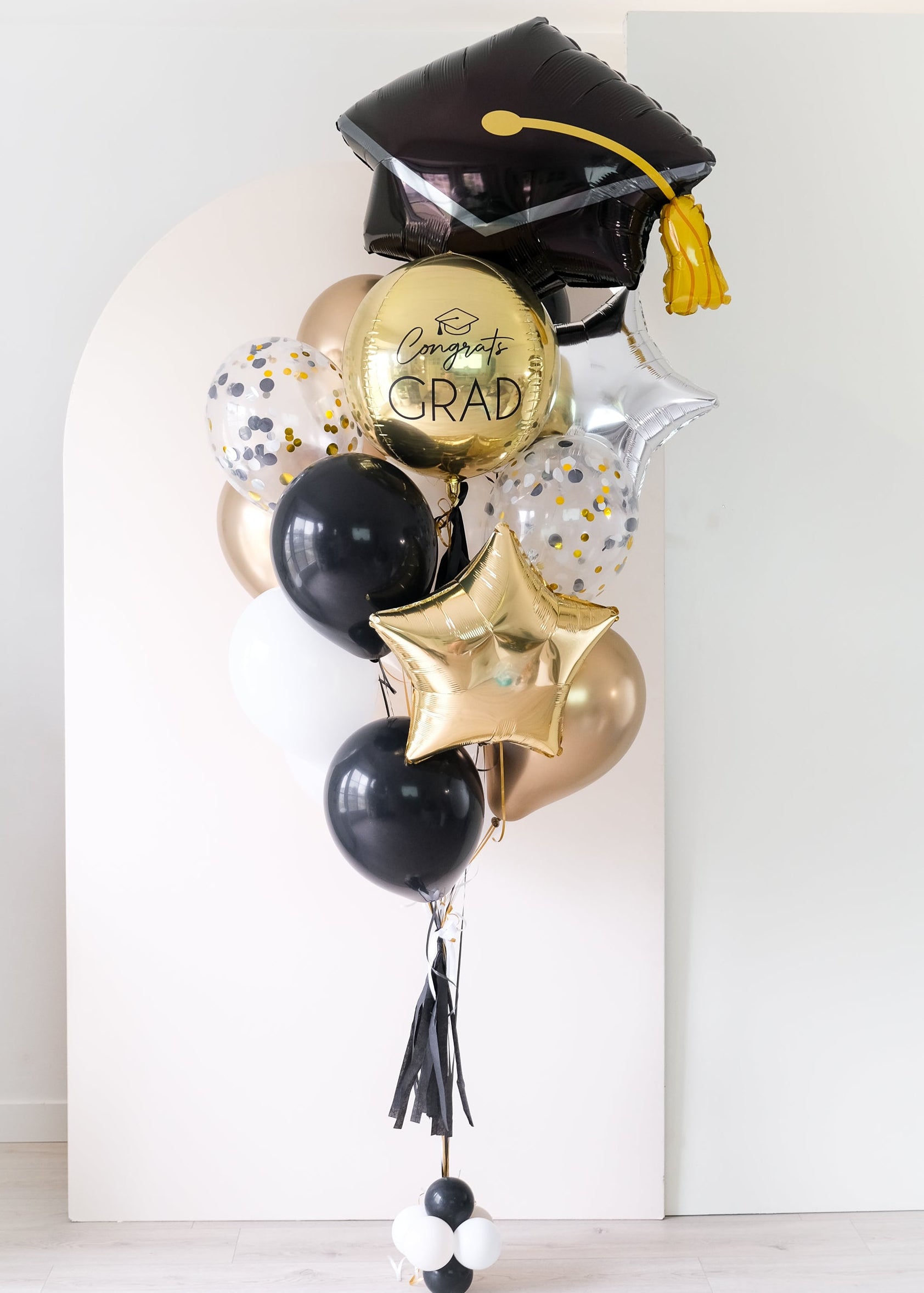 custom graduation balloons with grad cap shape in front of arch backdrop