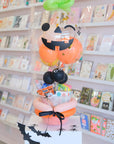 Decorative Halloween-themed balloon arrangement in a store setting with greeting cards.