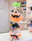 Halloween-themed plush toy with a pumpkin design in a bubble, on a table.
