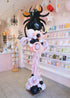 Balloon sculpture of a spider in a store setting with shelves and decor.