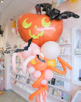 Decorative balloon arrangement with a pumpkin and bat in a store.