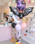 Halloween-themed balloon arrangement with a ghost and bat in a store setting.