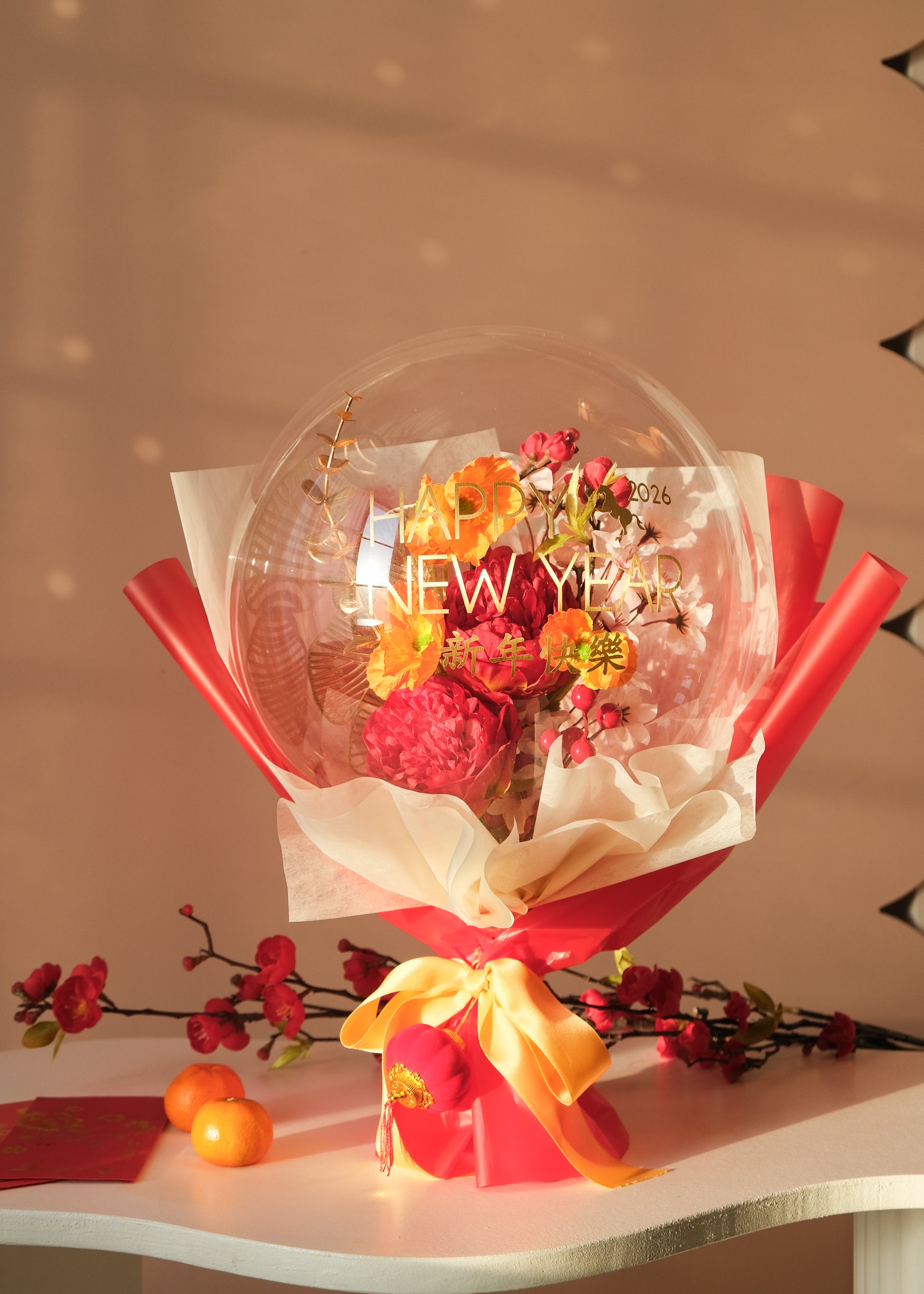 Lunar new year themed florals inside a balloon with tangerines and red envelopes on a table
