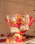 Lunar new year themed florals inside a balloon with tangerines and red envelopes on a table