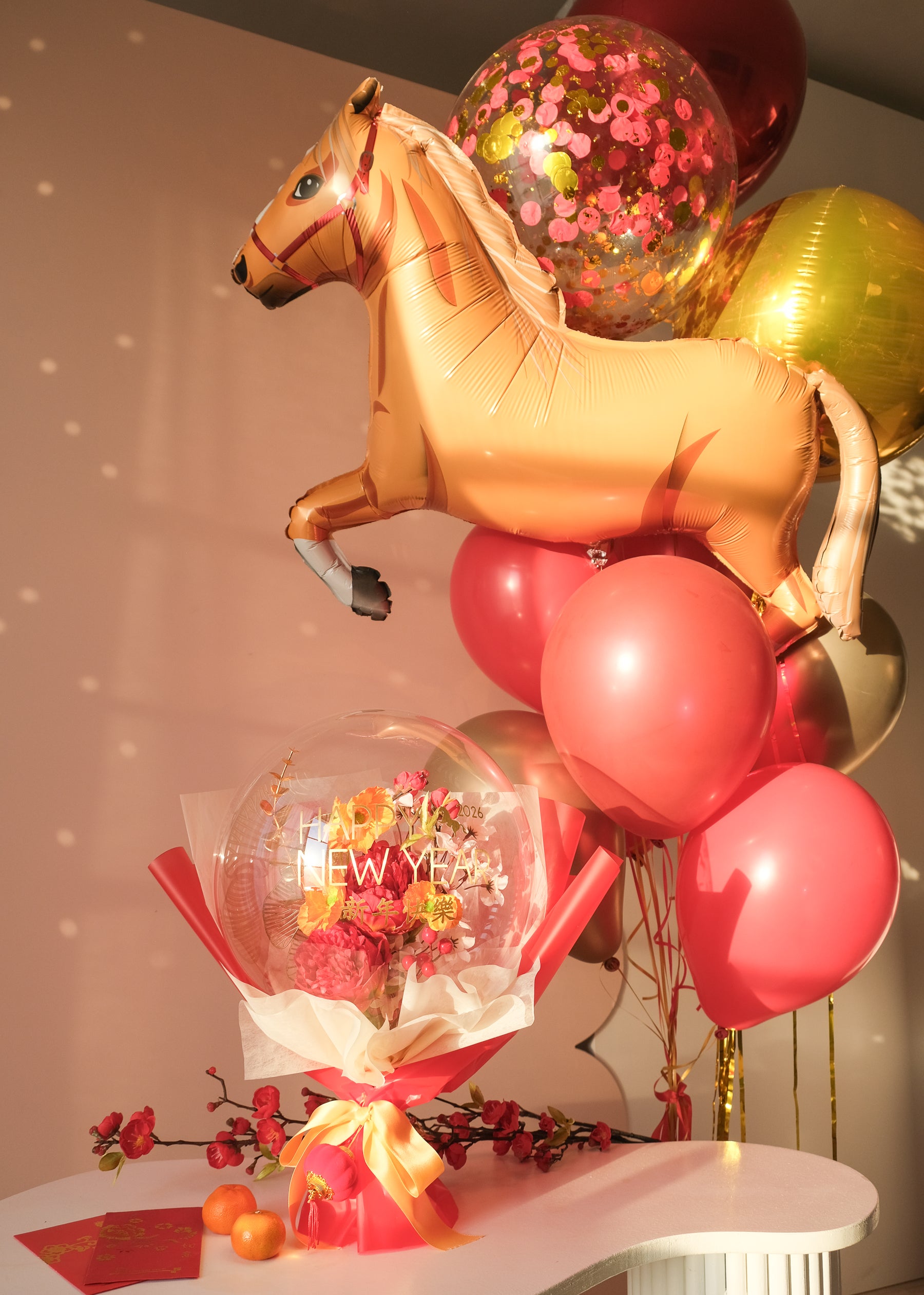 Lunar new year themed florals inside a balloon with tangerines and red envelopes on a table, with a horse balloon bouquet in the background