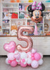 A balloon decoration with a Minnie mouse mylar balloon floating above, number 5 balloon and heart with a name.