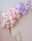A balloon garland featuring a progression of colors from purple to pink, with decorative flower accents.