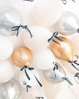 gold, silver and cream latex balloons with a black bow floating on the ceiling