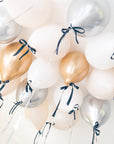 gold, silver and cream latex balloons with a black bow floating on the ceiling